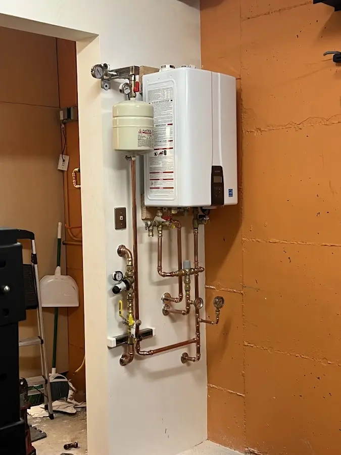 Plumbing technician inspecting water heater connections in East Greenbush